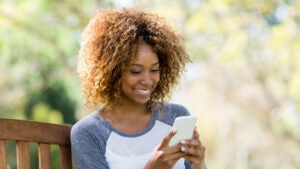 A woman takes a break from a walk in the park to track her menstrual cycle through an app on her smartphone.