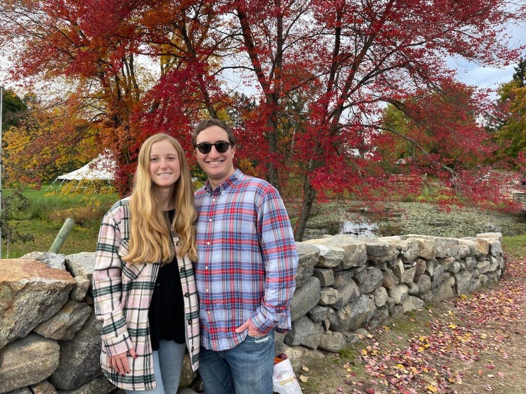 Abigail and Bobby standing under a red tree after apple picking