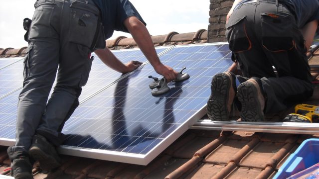 People installing solar panels on a roof.