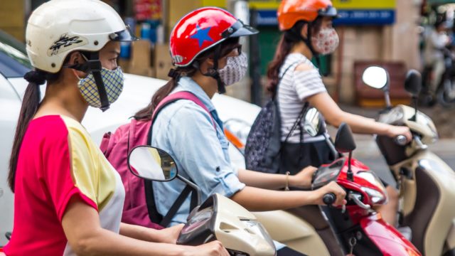 people in face masks on scooters