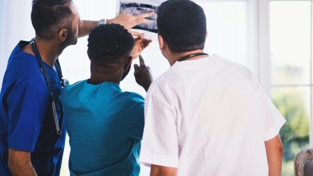 Three doctors review a medical scan