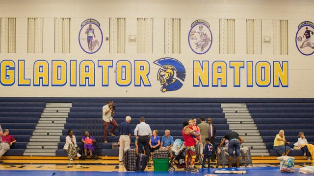 A group of people gather in a school gym serving as a hurricane shelter