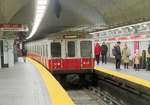 A Boston subway train leaving the station with people standing on the platform