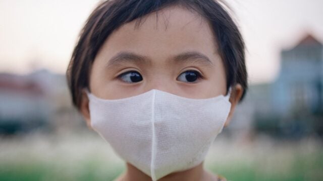 Young child wears a face mask outside
