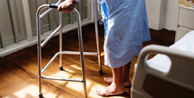 A man in a hospital gown stands with a walker