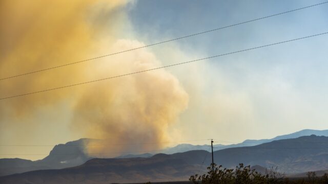 Orange wildfire smoke billows into the sky.