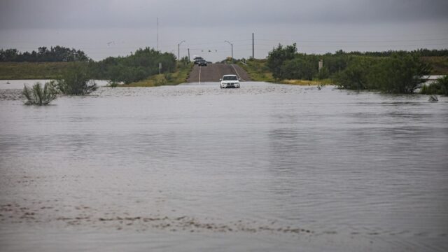A car is blocked by a flooded roadway
