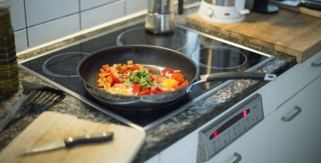 Eggs and vegetables are cooked in a pan on an induction stove.