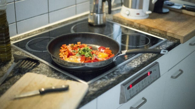 Eggs and vegetables are cooked in a pan on an induction stove.