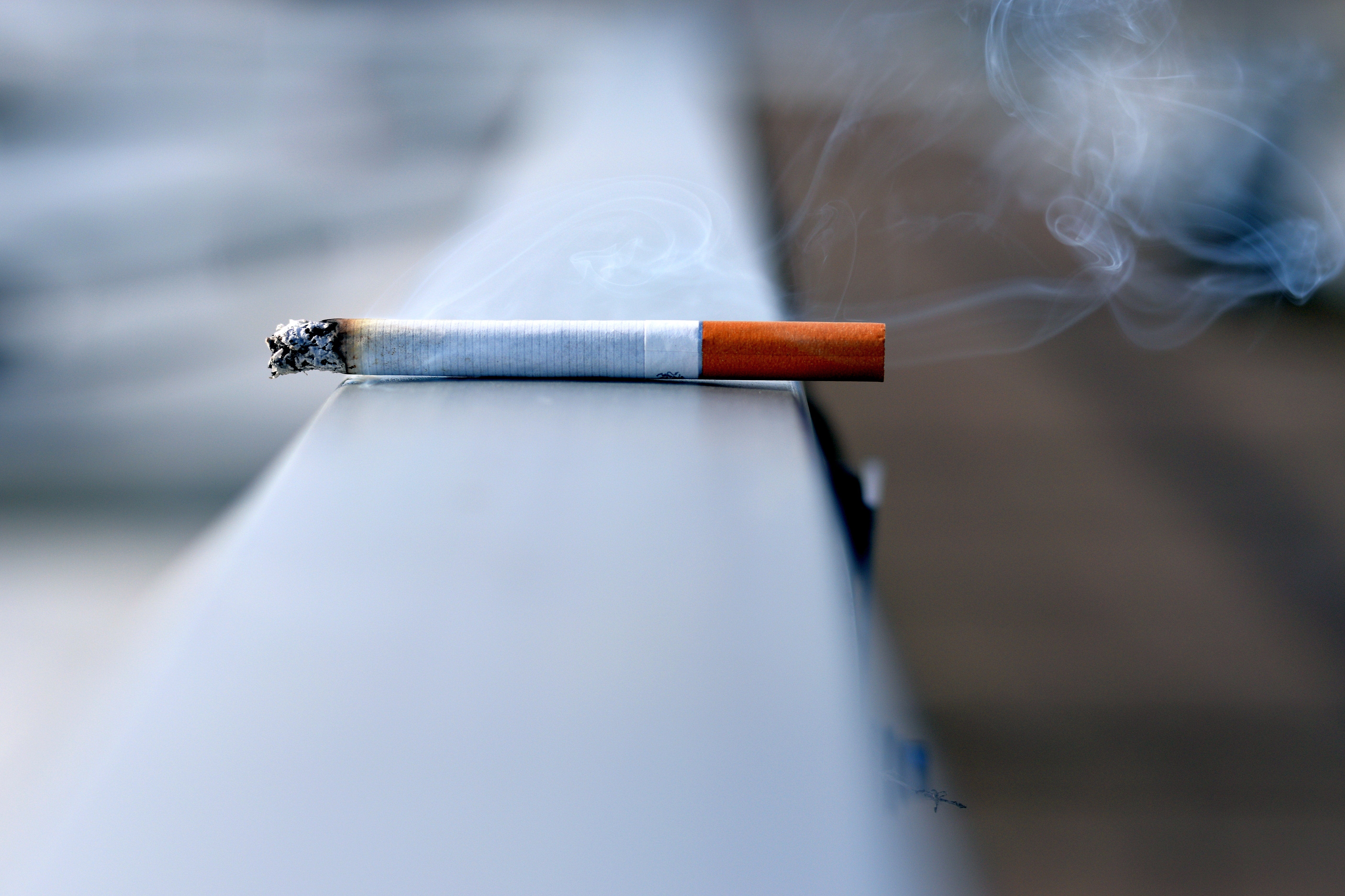 A smoking cigarette lying on a ledge.