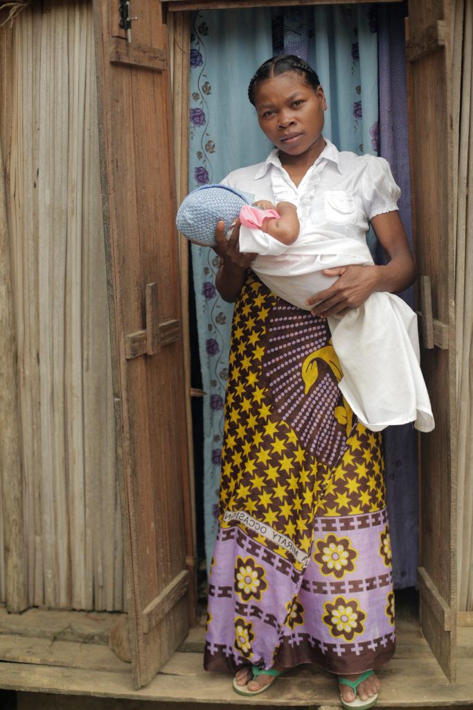 Woman holds baby standing in doorway