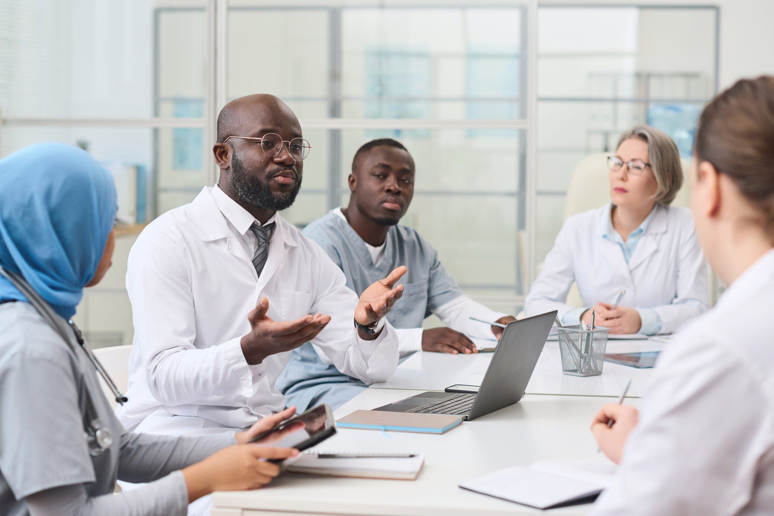 Doctor talking to other doctors and nurses at meeting