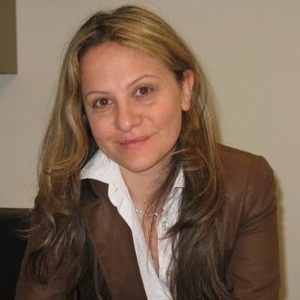 Elena Savoia wears a brown jacket and white shirt