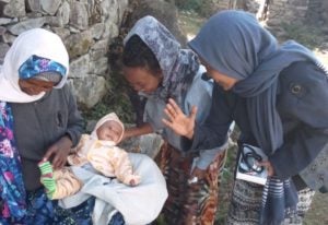 Three women with smiling baby in Ethiopia