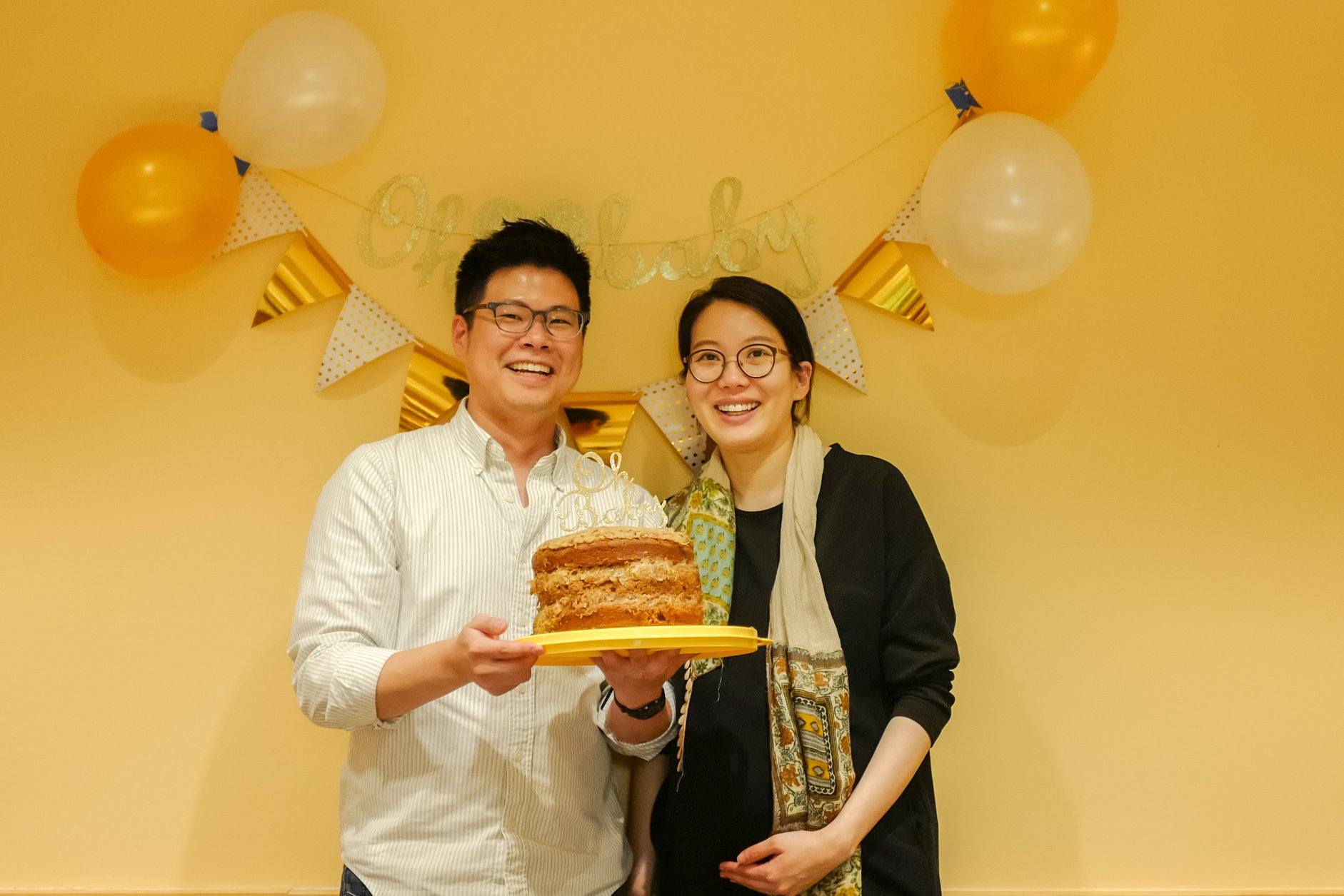 photo of couple holding a cake in front of balloons