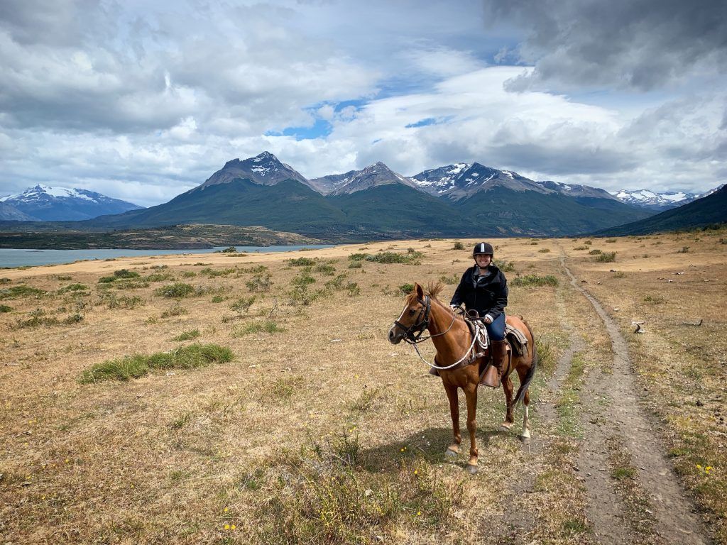 student on horse in field in front of mountain landscape