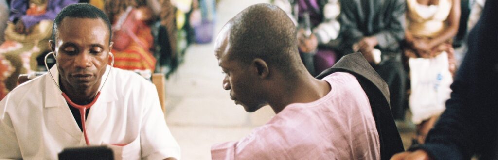 Doctor measuring blood pressure to a patient in Nigeria - photo by Dominic Chavez