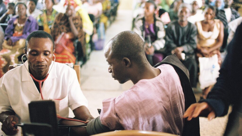 Doctor measuring blood pressure to a patient in Nigeria - photo by Dominic Chavez