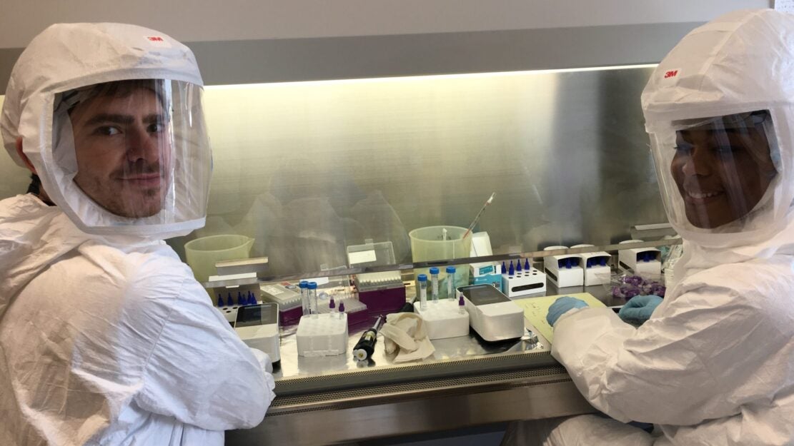 Two members of the Kanki Lab working at the bench, wearing personal protection equipment.