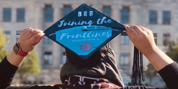 2020 Graduate pictured from behind with cap that reads "be right back, joining the frontlines"
