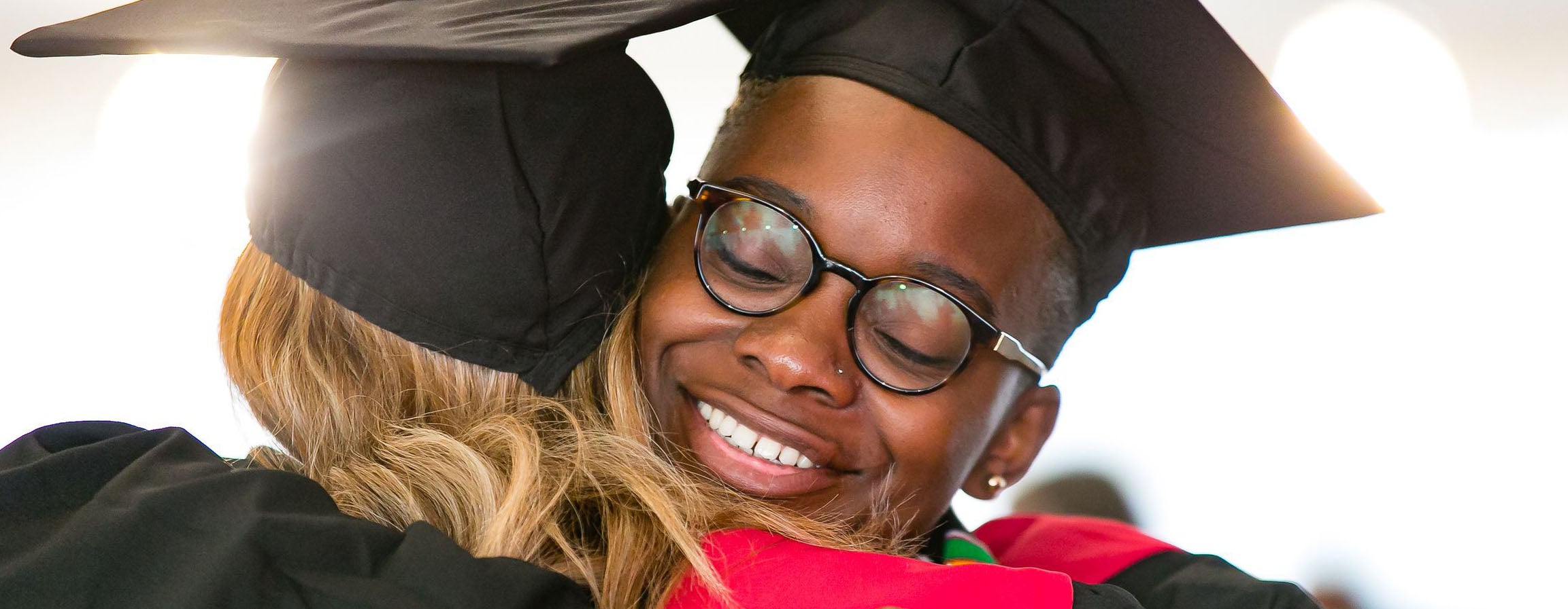 Smiling graduate embraces a fellow classmate