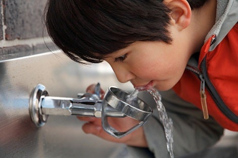 child drinking water from school water fountain