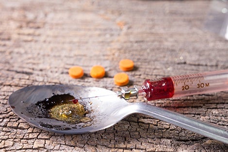 Drug syringe, amphetamine tablets, and cooked heroin