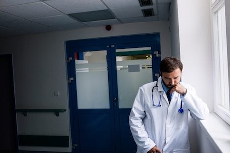 Sad doctor standing in corridor