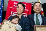Father and baby with award