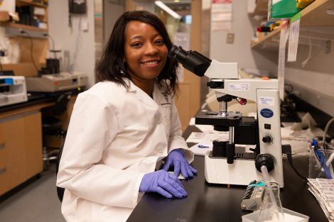 Lola Fagbami in a research lab, sitting by microscope