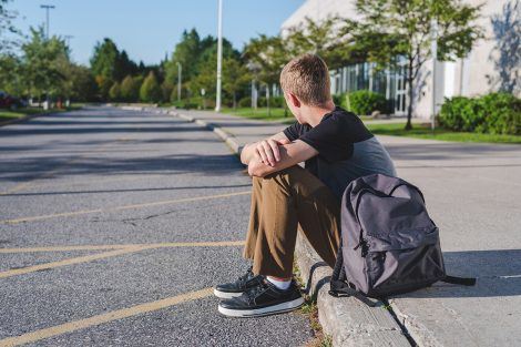 A boy sitting on a curb.