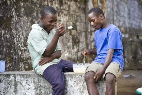 Two African teen boys eating rice