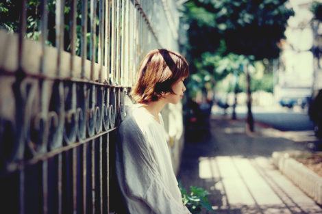 A lone woman leaning on a fence