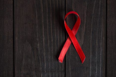 Red ribbon on wooden background-AIDS