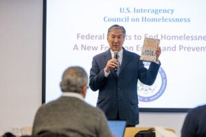 Howard Koh displays new book about Jim O'Connell's work to bring health care to people experiencing homelessness.