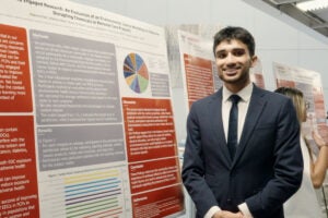 Humza Irfan standing in front of his research poster.