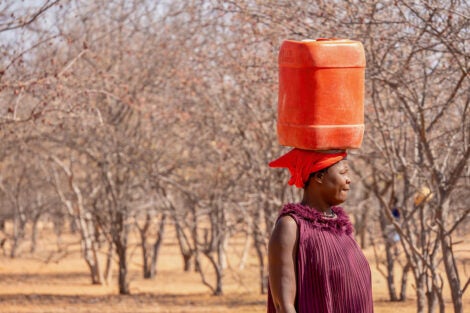 In rural Namibia, a woman carries a plastic container of drinking water on her head.