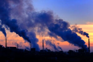 Pollution pours from factory smokestacks at sunset