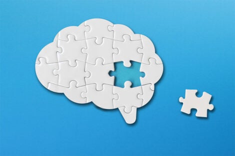A jigsaw puzzle in the shape of a brain. One piece is taken out.