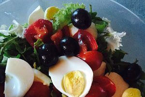 Hardboiled eggs on a salad of tomatoes, greens, and olives