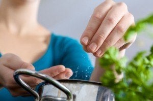 Woman adding salt to pot