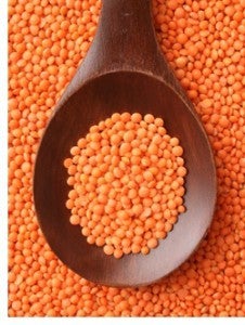 Large wooden spoon full of red lentils