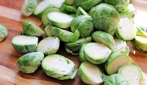 Brussels sprouts cut in half lying on a wooden cutting board
