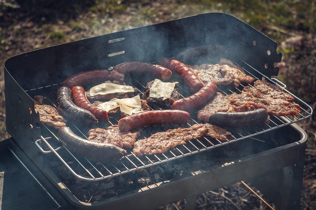 hot dogs and red meat on a grill