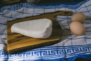 a cloth with goat cheese on a wooden board and two eggs