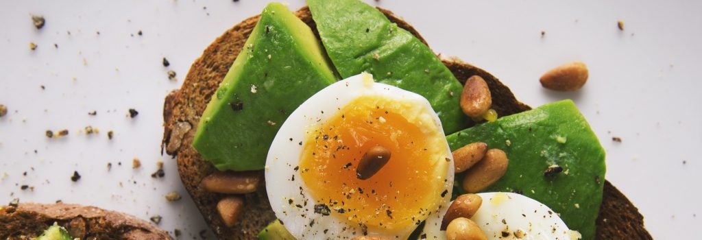 avocado, soft boiled eggs with yolks, and pinenuts on toast