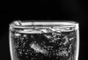 glass of ice water on black background