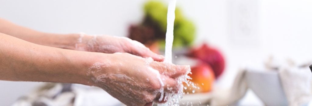 washing hands with soap and water with produce in the background