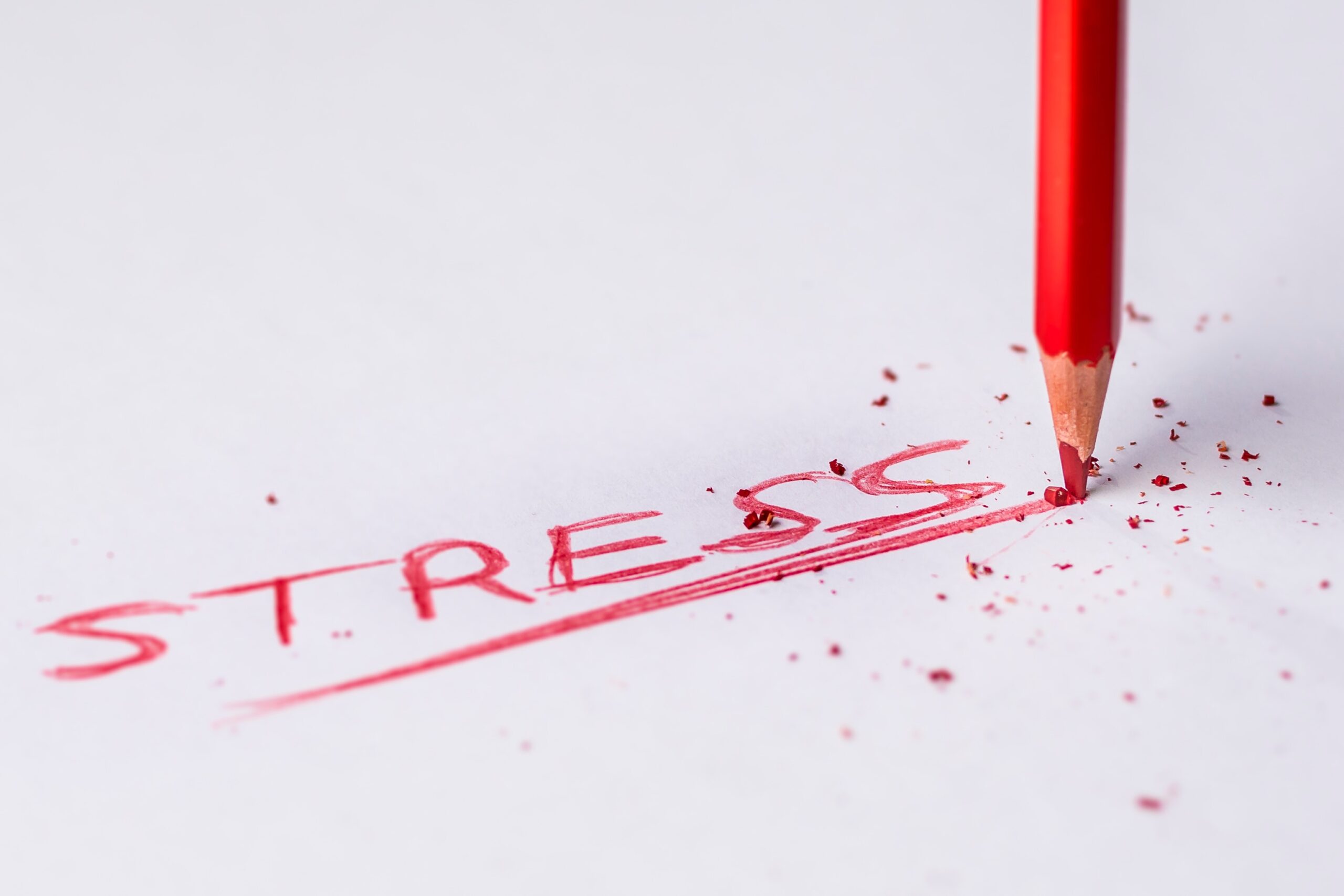 the word stress written out in a red colored pencil, with pressure being applied to the pencil causing the tip to break