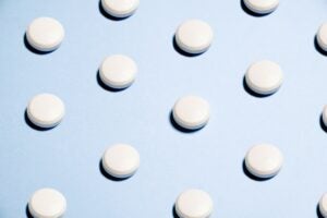 white circular pill supplement on a light blue background